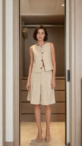 Front view of woman wearing beige sleeveless top and bermuda shorts set