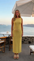 Front view of woman wearing yellow sleeveless midi dress with waist chain