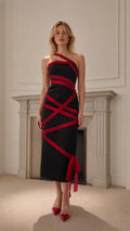 Front view of black asymmetric midi dress with red ribbon details