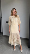 Front view of model wearing cream open-knit cardigan and matching midi skirt set