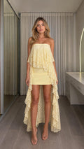 Front view of woman wearing yellow strapless high-low lace dress