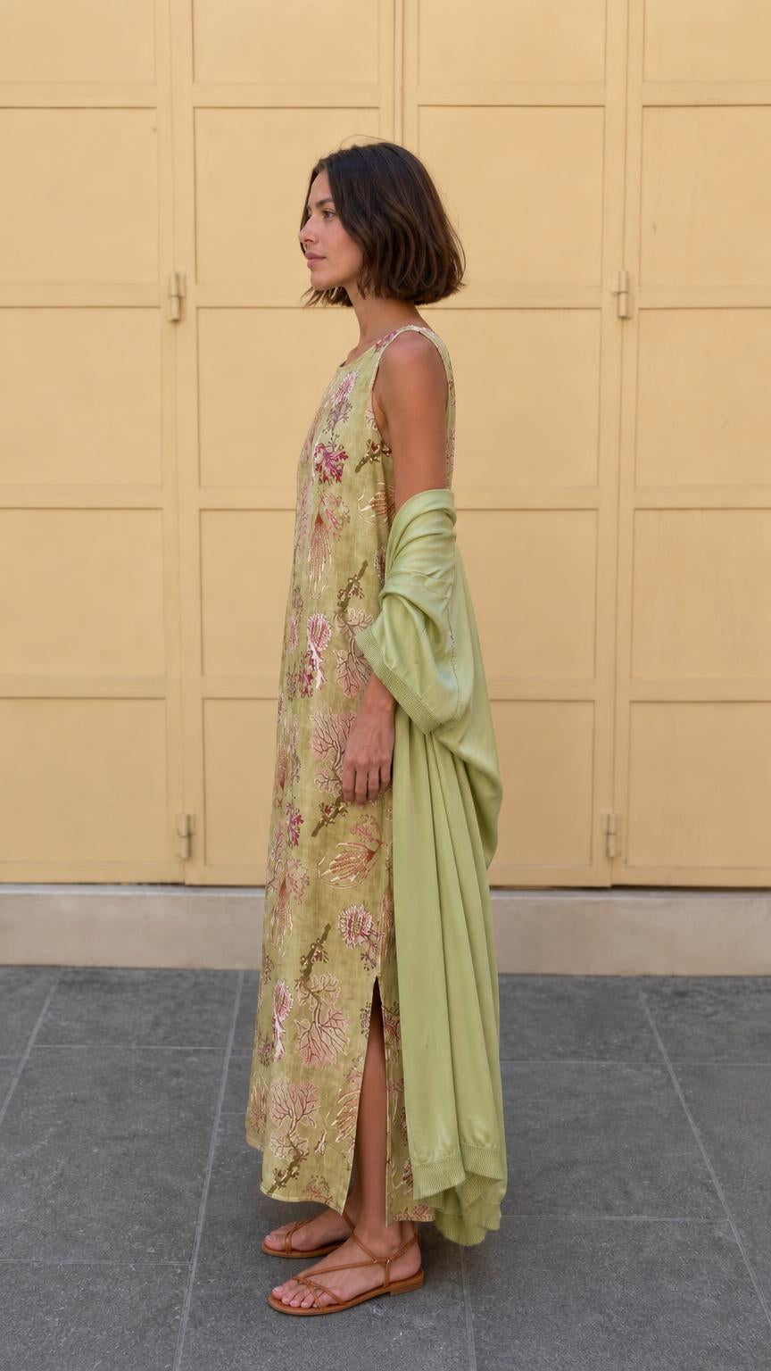 Side profile of model in olive floral maxi dress showing side slit