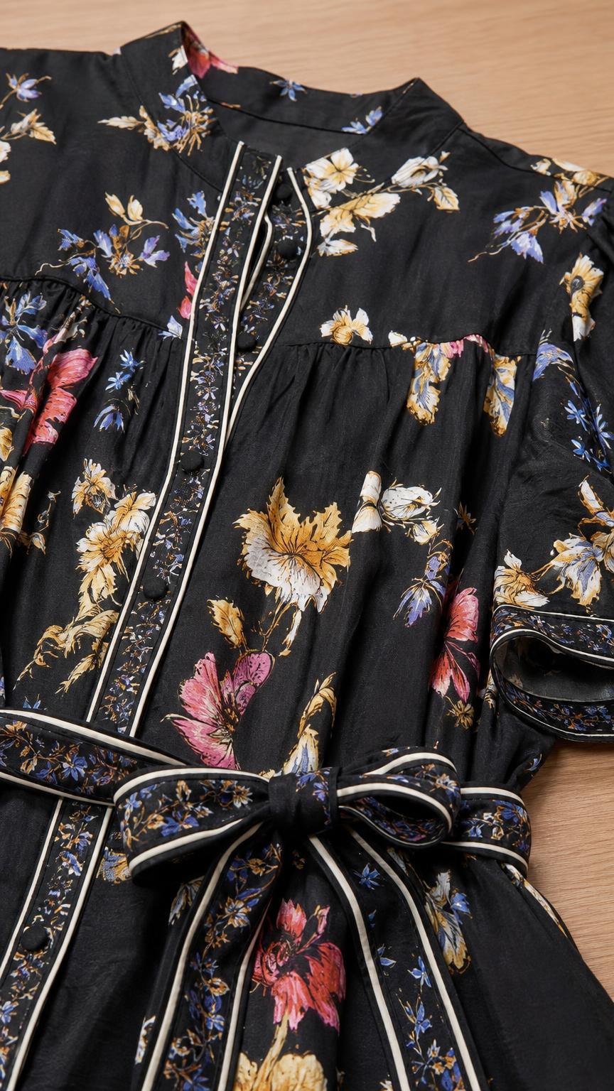 Close-up detail of Black floral dress fabric, buttons, and belt