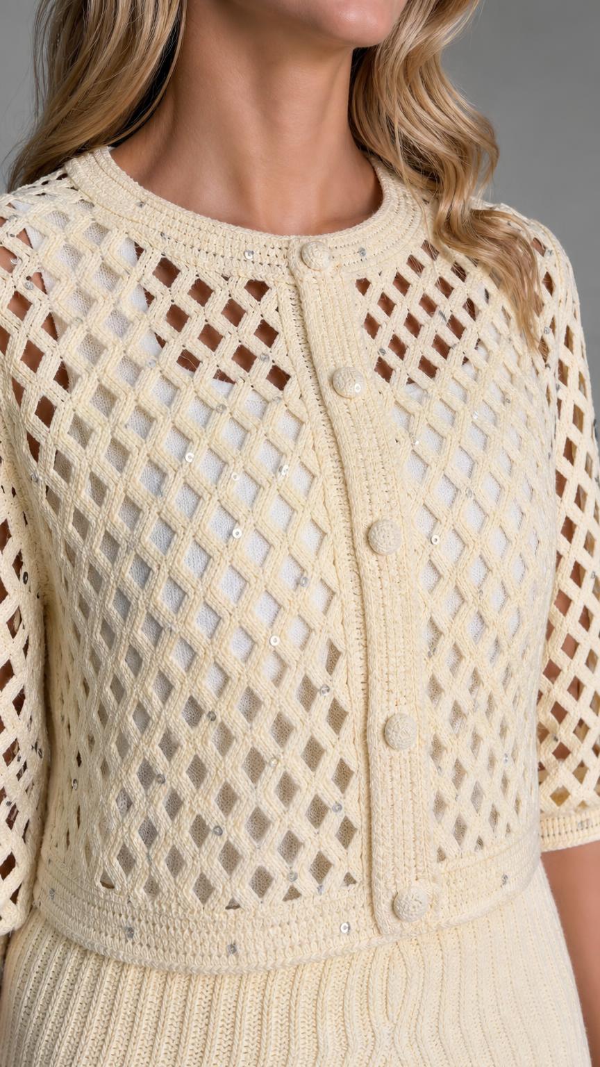 Close-up detail of the crewneck open-knit cardigan texture and buttons