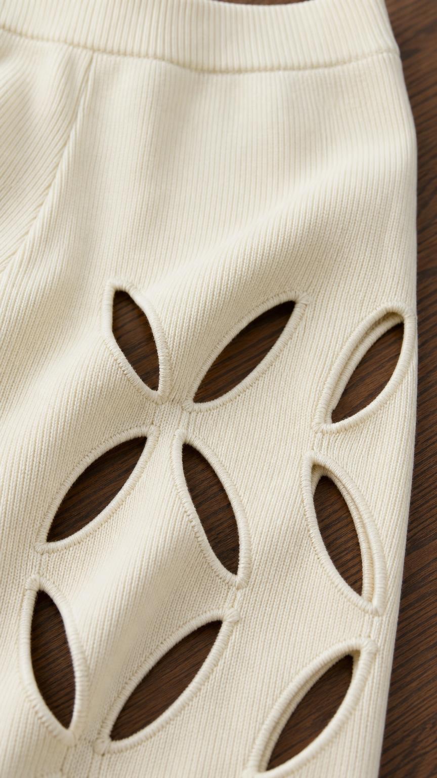 Close-up detail of geometric cutout pattern on ivory knit pants