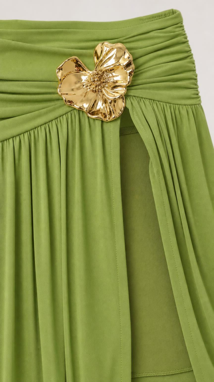 Close-up detail of the gold metallic flower accent on the olive green skirt waistband