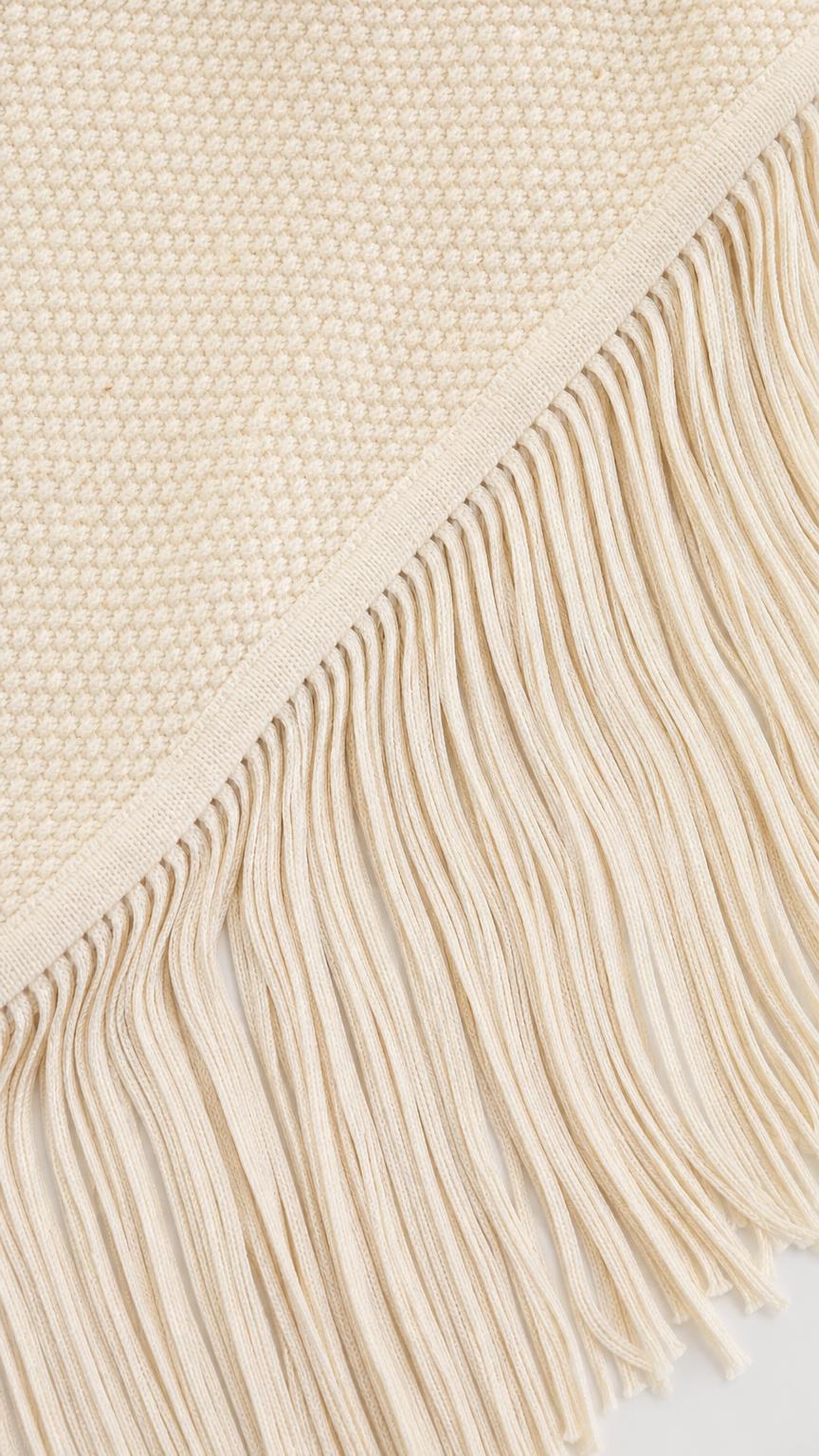 Close-up detail of the textured knit fabric and fringe hem