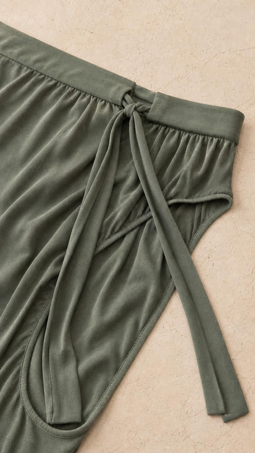 Close-up detail of the waistband and fabric texture of the sage green pants