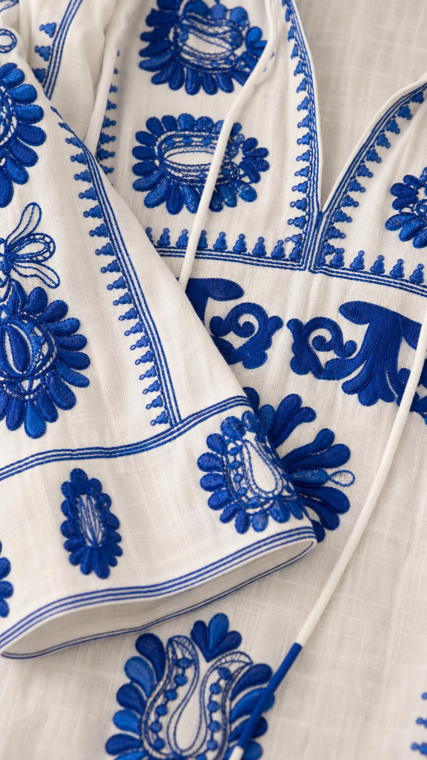 Close-up detail of blue embroidery on white fabric