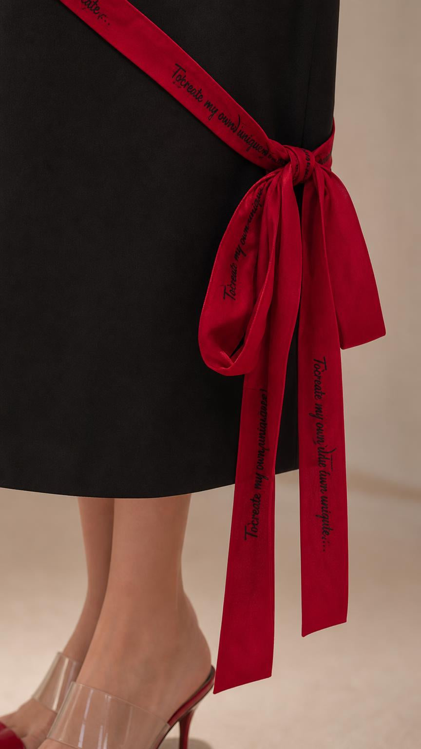 Close-up of red ribbon tie and bow detail on dress hem