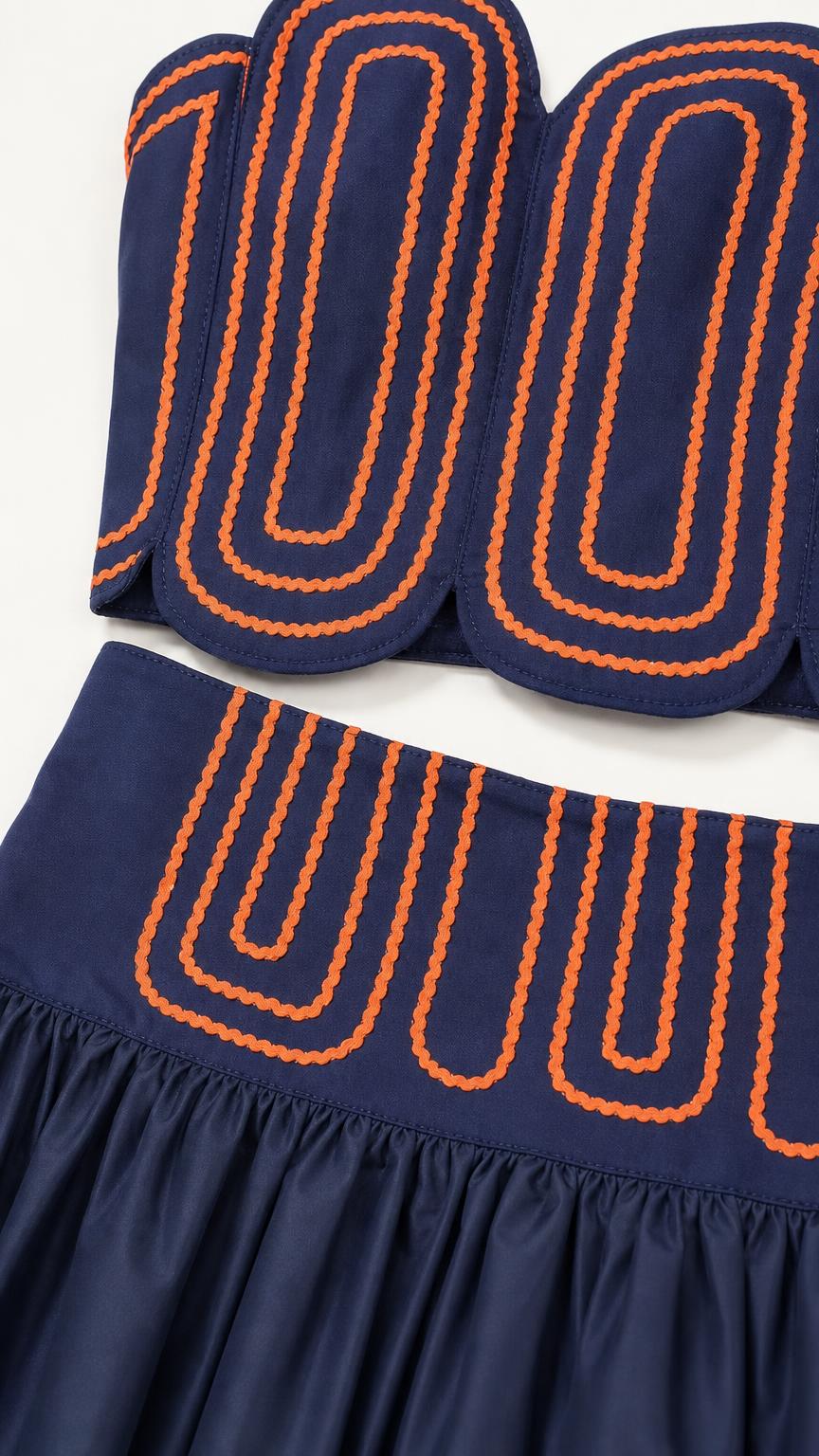 Close-up detail of embroidered wave pattern on crop top and waistband