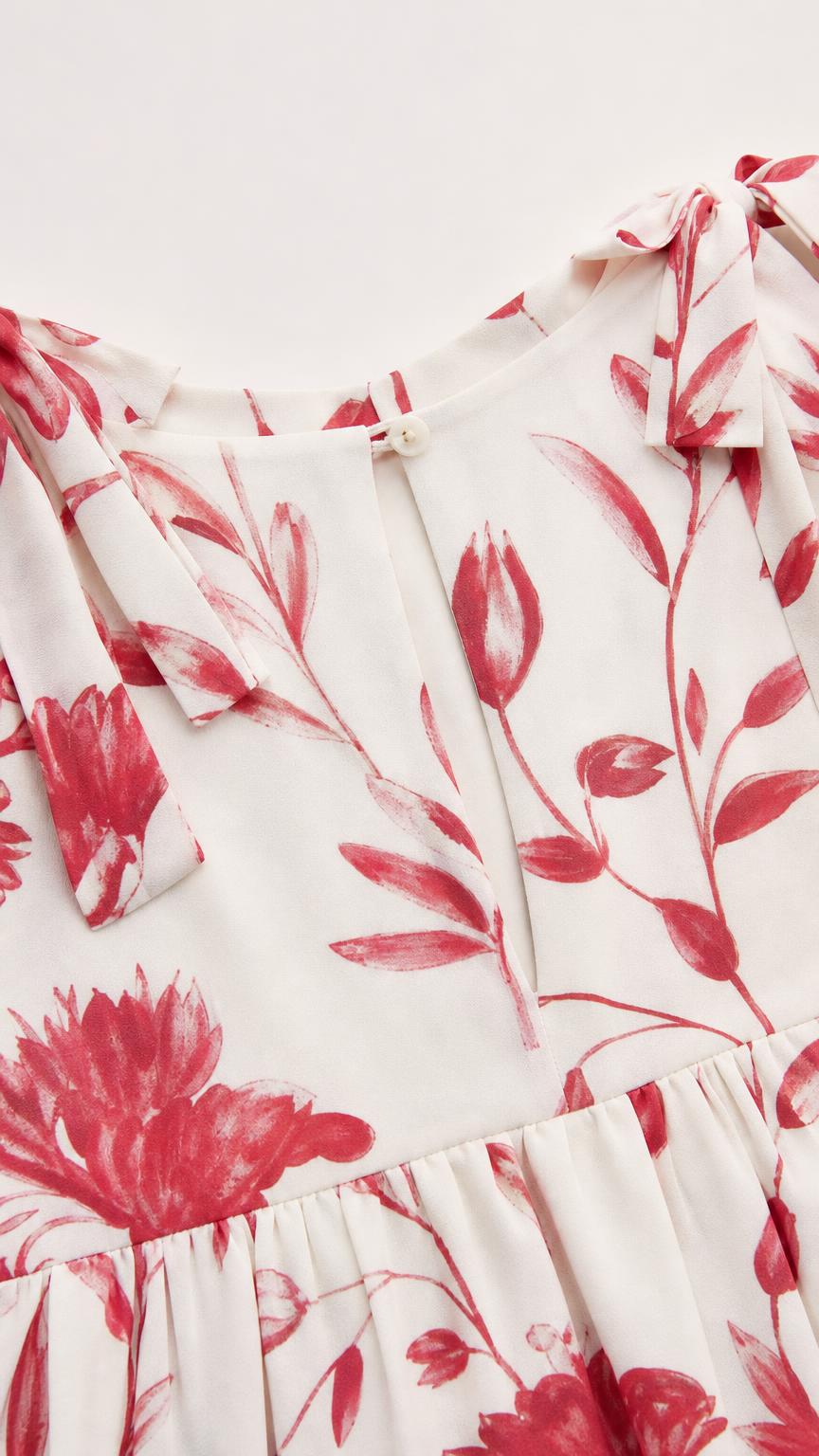 Close-up detail of white floral fabric, neckline, and shoulder tie