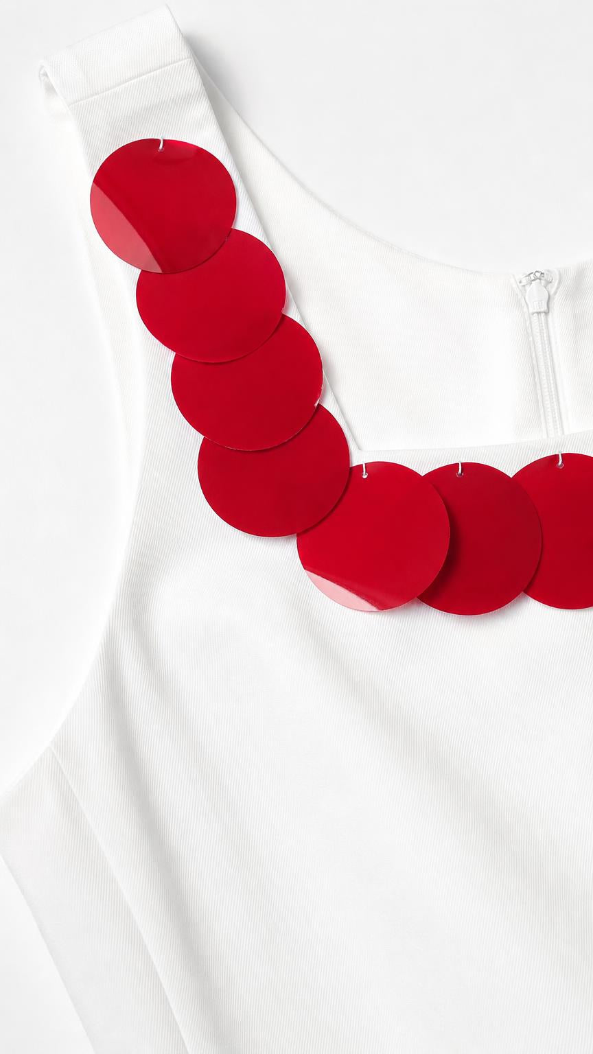 Close-up detail of red circular sequin trim on white top neckline