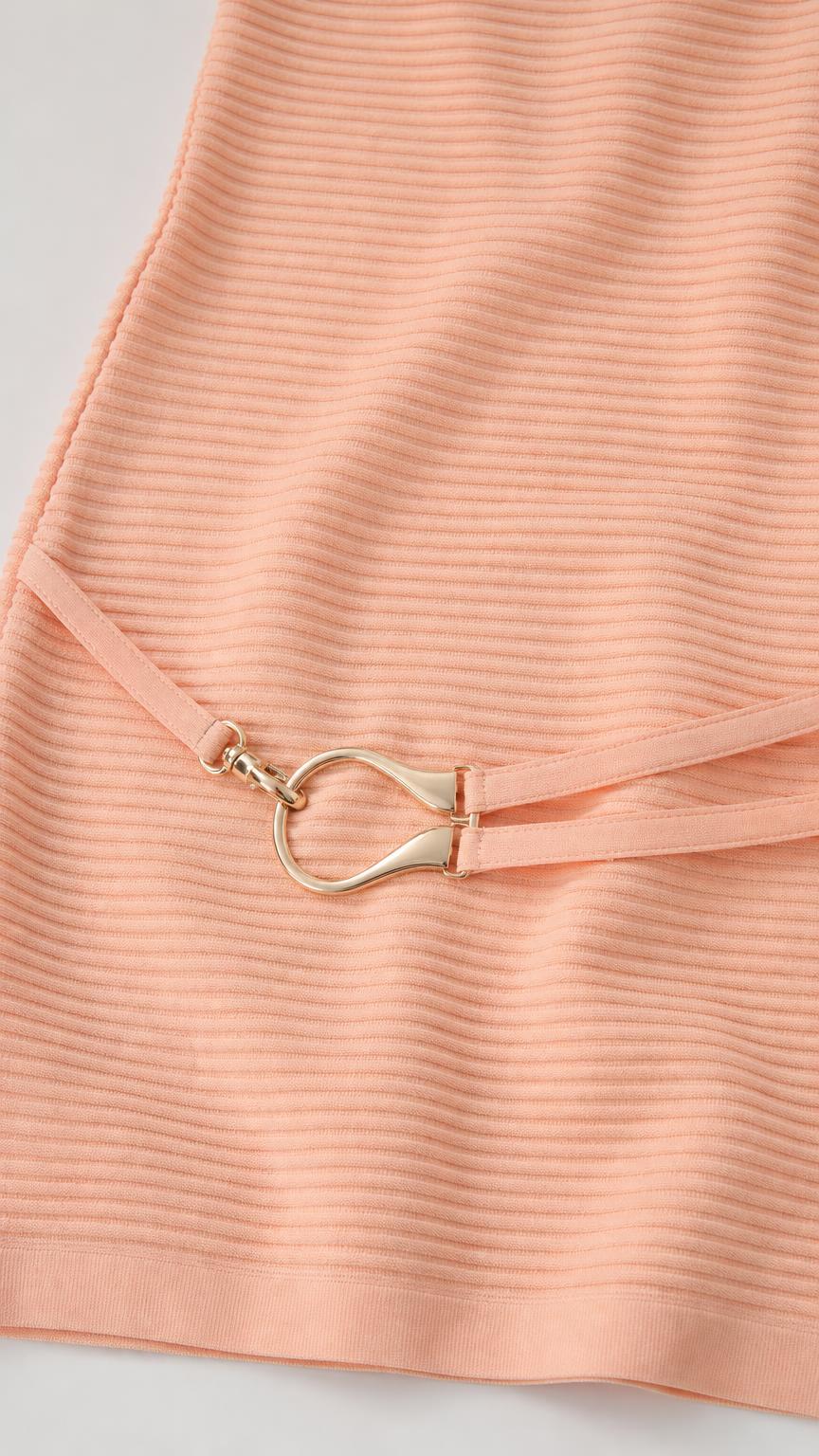 Close-up detail of the gold-tone metal ring belt on peach ribbed knit dress