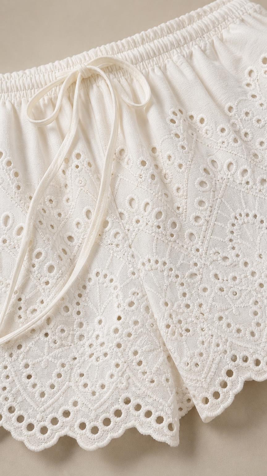 Close-up detail of the white eyelet shorts featuring drawstring and scalloped hem