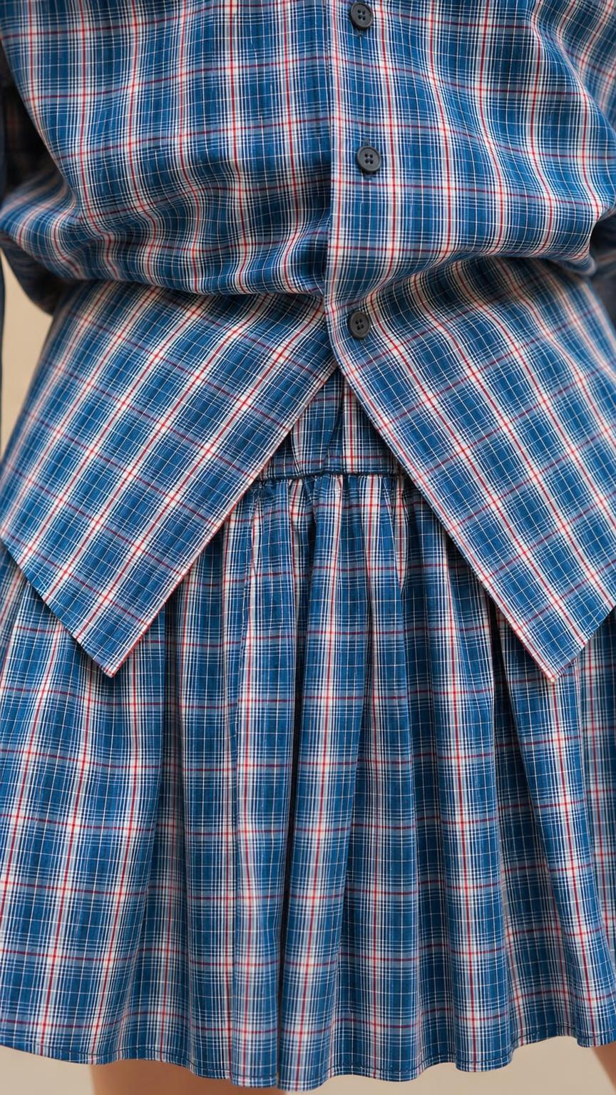 Close-up detail of blue plaid shirt button closure and pleated skirt overlay