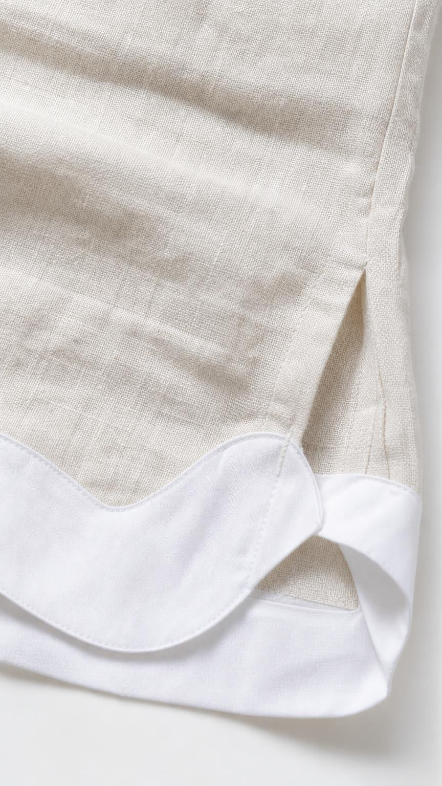 Close-up detail of white scalloped hem trim on beige fabric