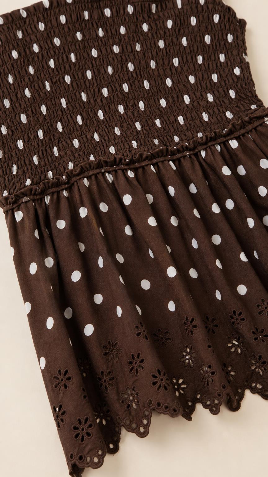 Close-up detail of smocked bodice and eyelet hem on brown dress