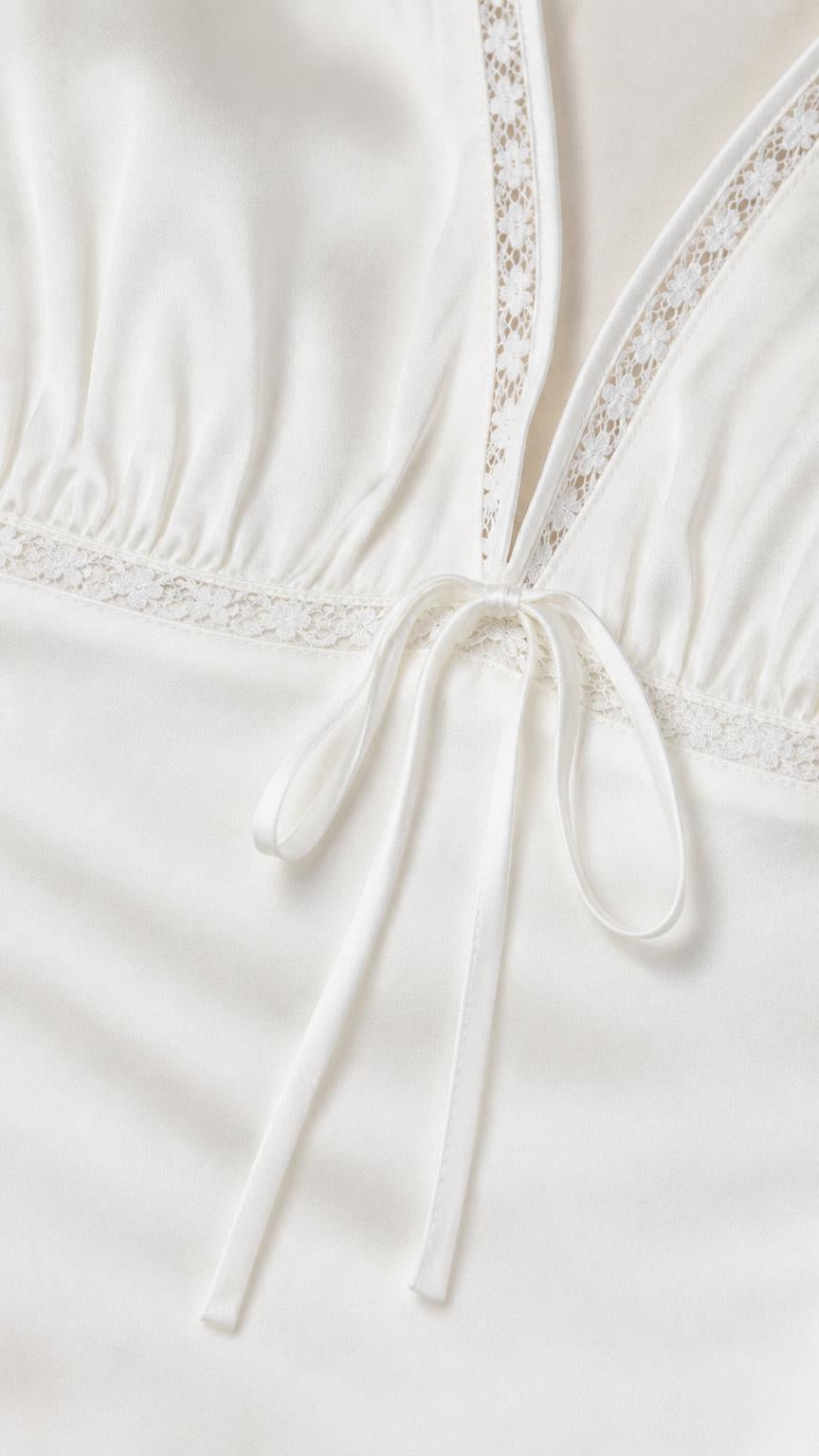Close up of lace trim and front tie detail on white dress