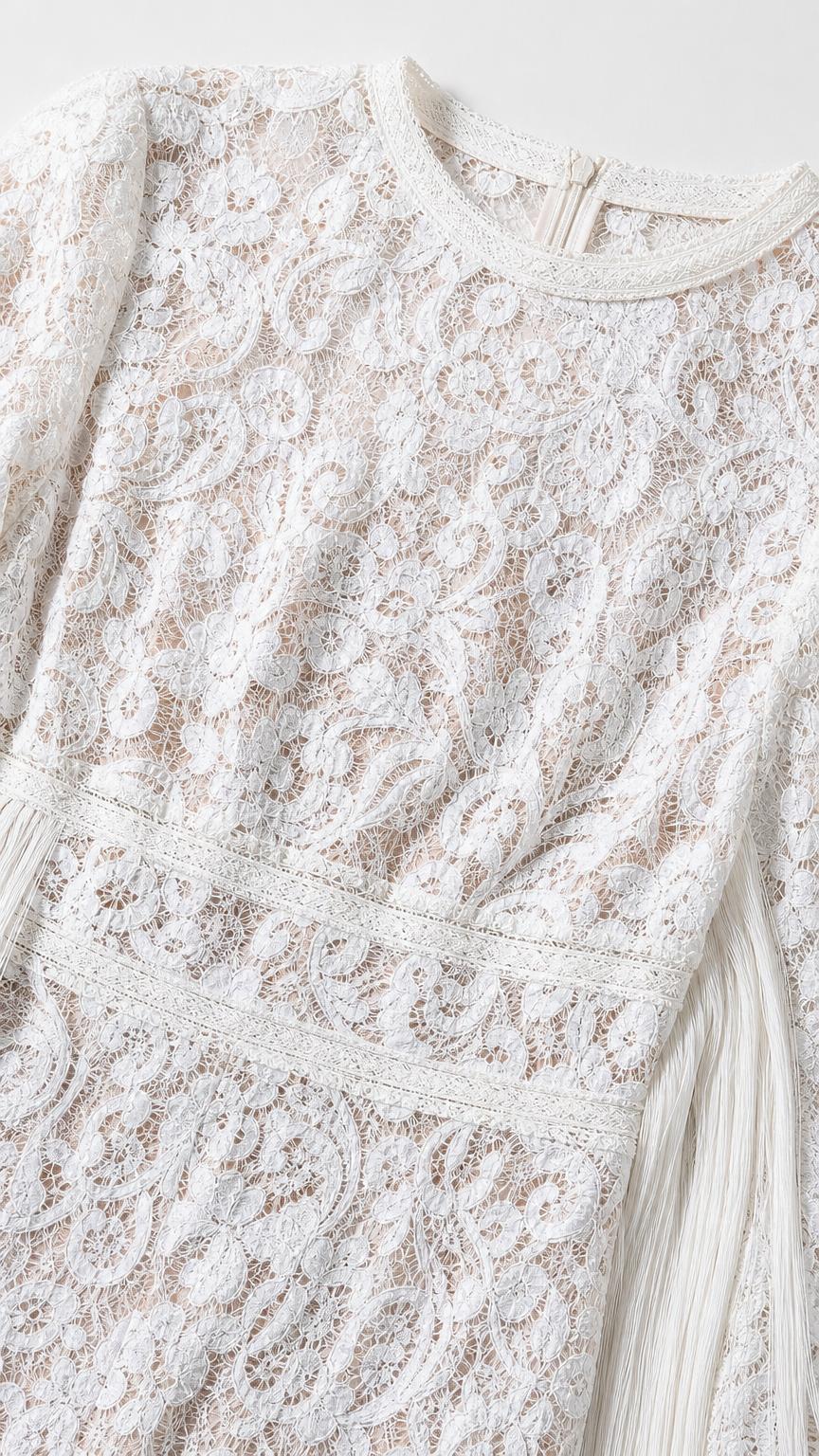 Close-up detail of lace pattern and round neckline on white jumpsuit