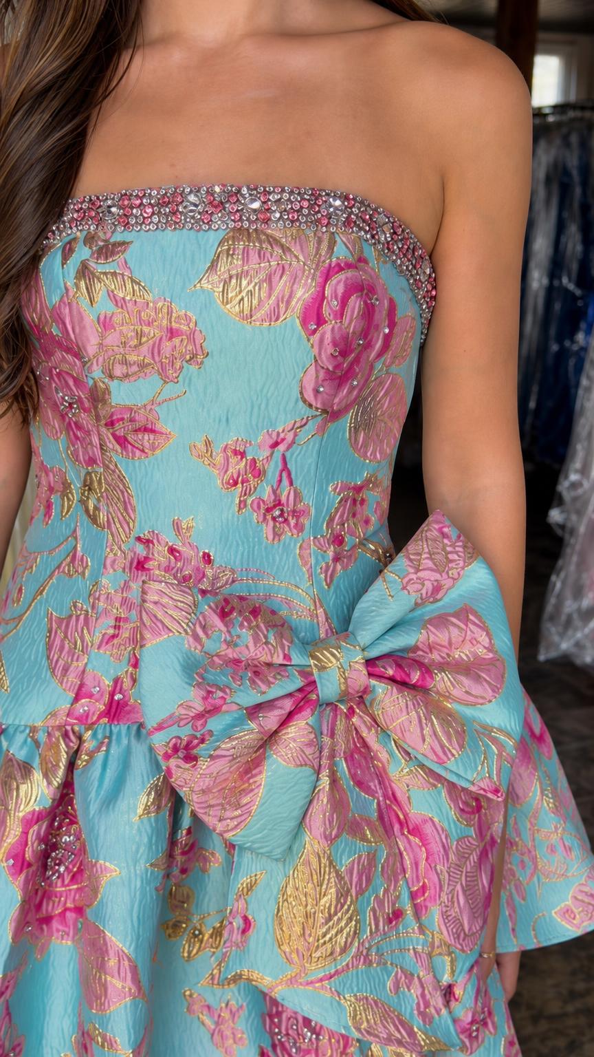 Close-up detail of crystal-trimmed neckline and waist bow on blue floral dress