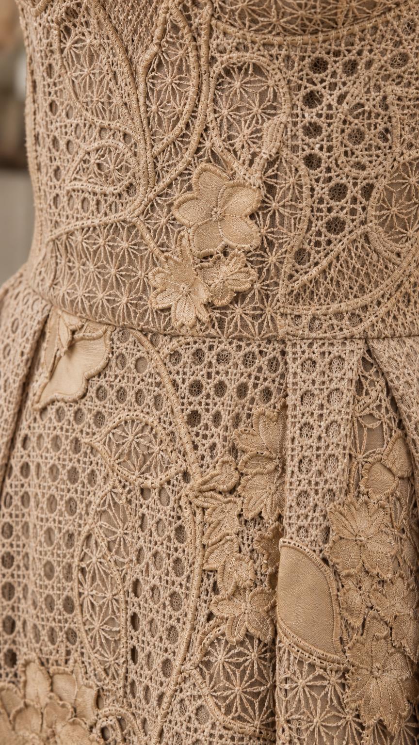 Close-up detail of lace pattern and floral appliqués on khaki dress