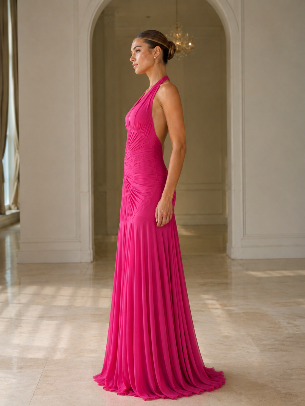 Side view of hot pink halter mermaid gown with floor-length drape